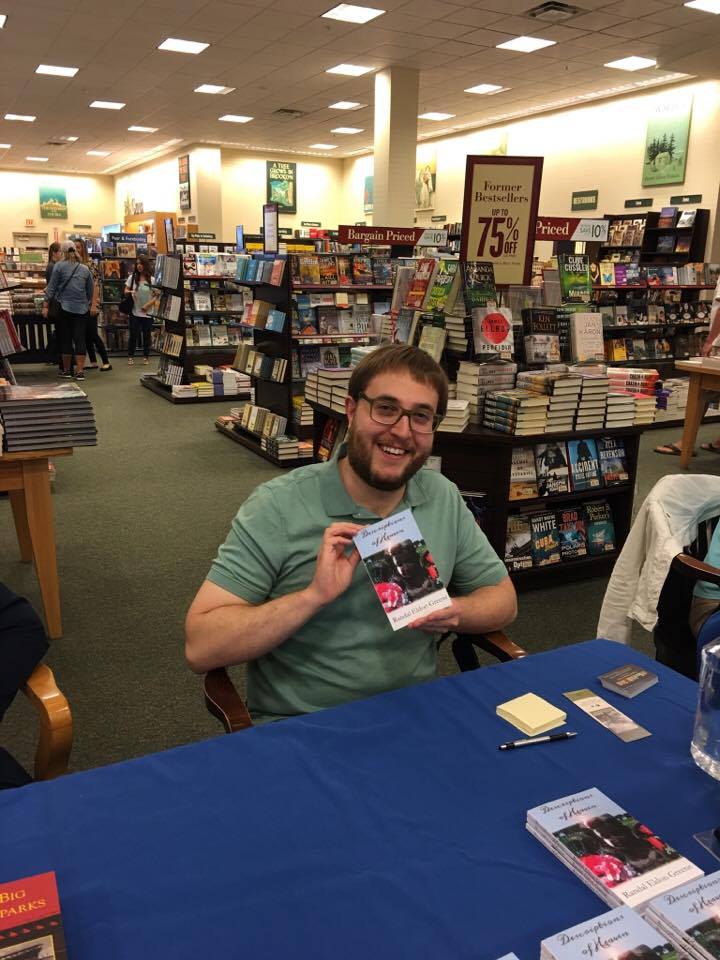 Literary Fiction writer Randal Eldon Greene holding up a copy of his novel Descriptions of Heaven.